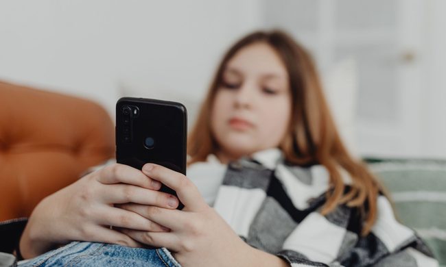Girl using a black phone while lying down