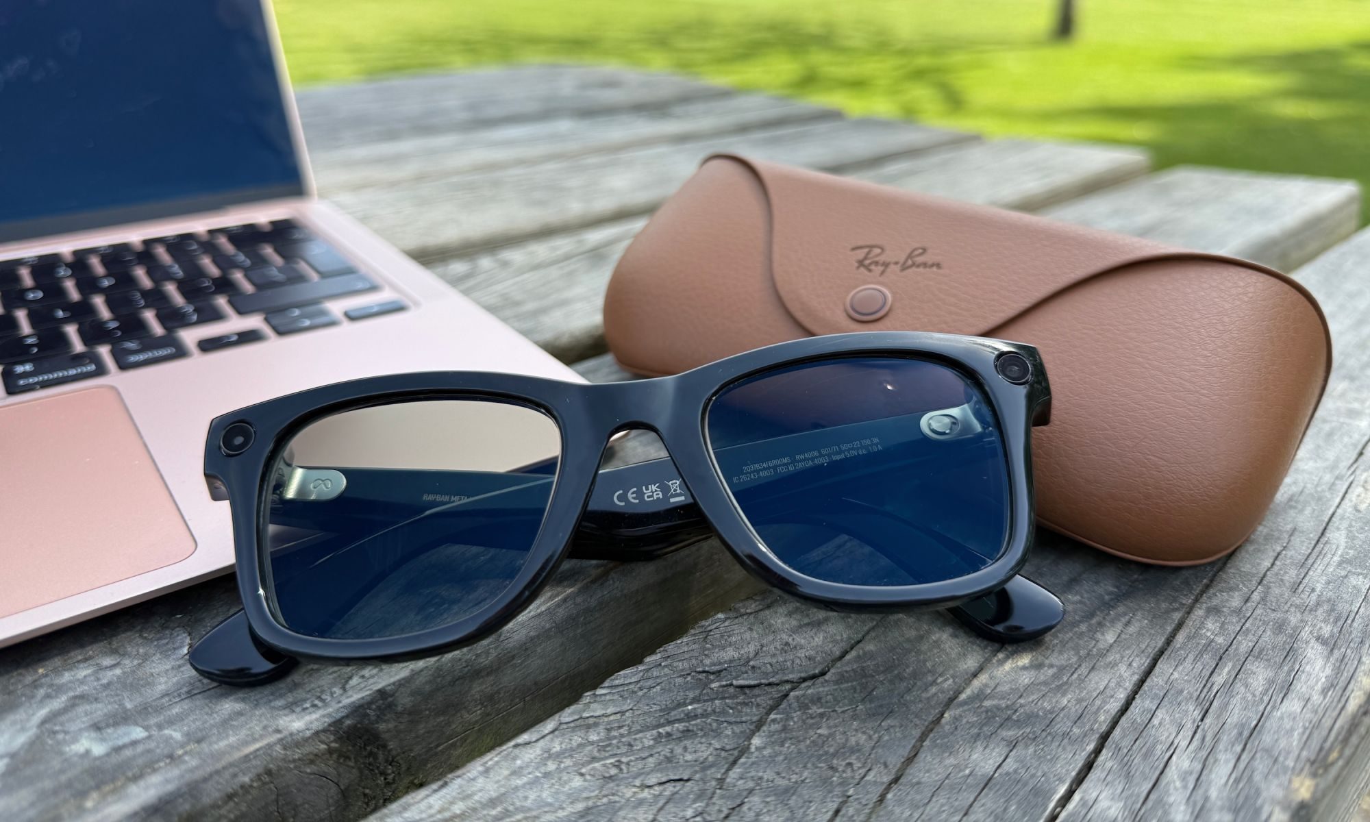 Ray-Ban Meta smart glasses on table next to case and laptop