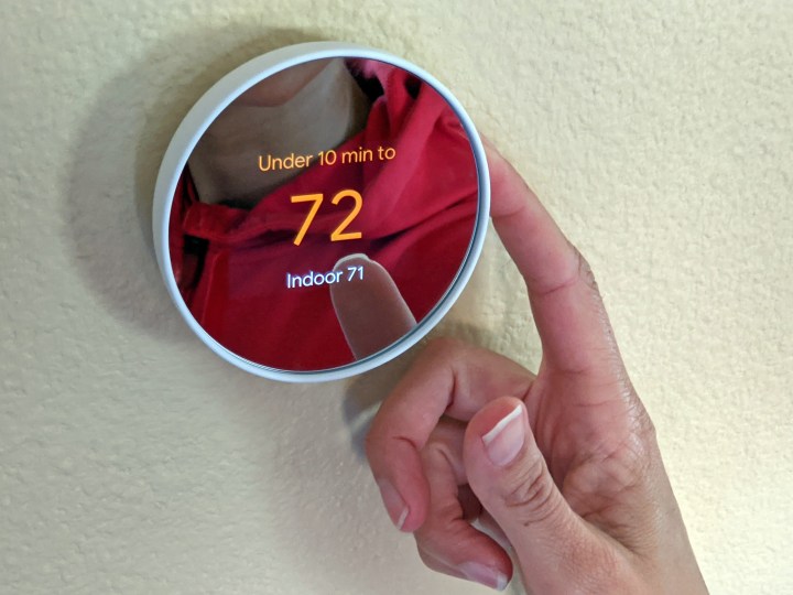 A person operating the Google Nest thermostat.