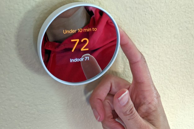 A person operating the Google Nest thermostat.