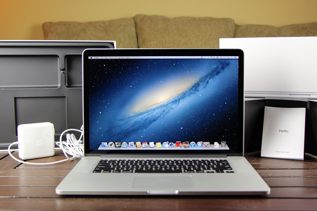 Um MacBook Pro em uma mesa com uma fonte de alimentação atrás dele.  O sistema operacional OS X Mountain Lion está visível em seu visor.