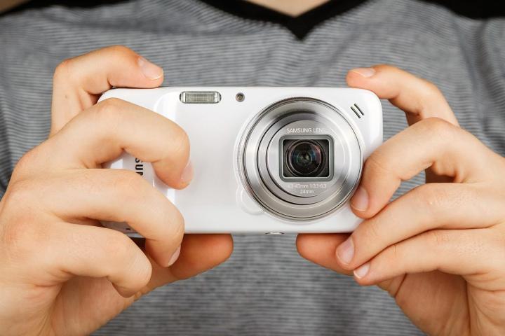 Person holding Samsung Galaxy S4 Zoom white color.