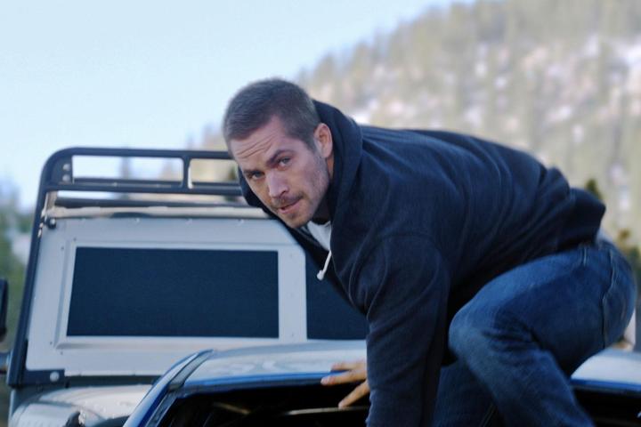 Paul Walker stands on the edge of a bus in Furious 7.
