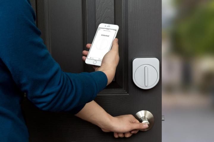 A person using their phone to unlock the Sesame Smart Lock on their door.