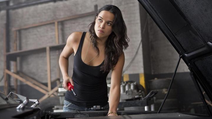 Michelle Rodriguez stands over a car in Fast 6.