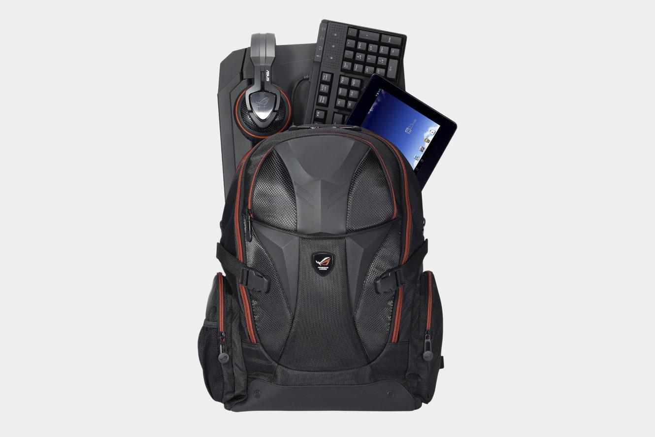 An Asus ROG Nomad V2 backpack with various tech products sticking out of it: a pair of headphones, a keyboard, and a tablet.