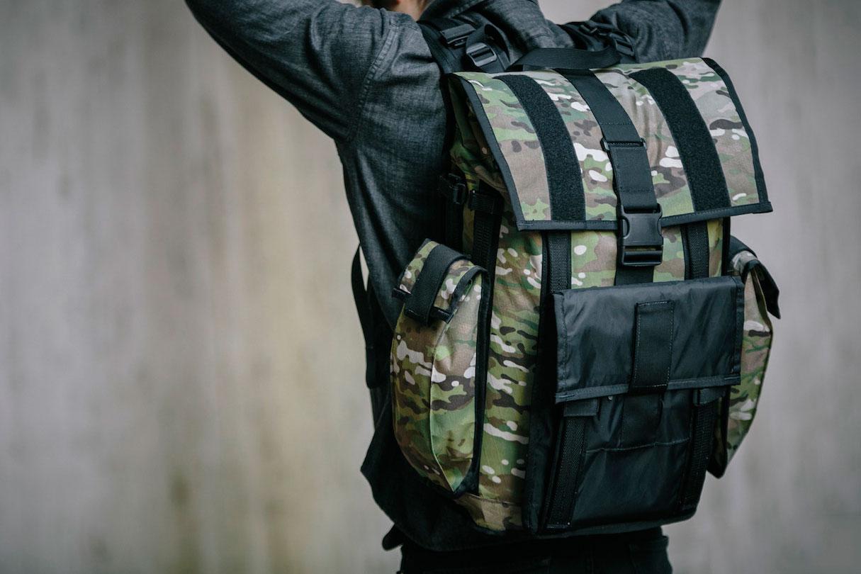 A close up profile rear view of a person wearing a Mission Workshop R6 Arkiv Field Pack, in a different color.