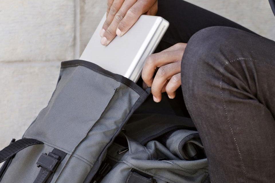 Close up of a person's hands putting a white item into a Mission Workshop R6 Arkiv Field Pack.