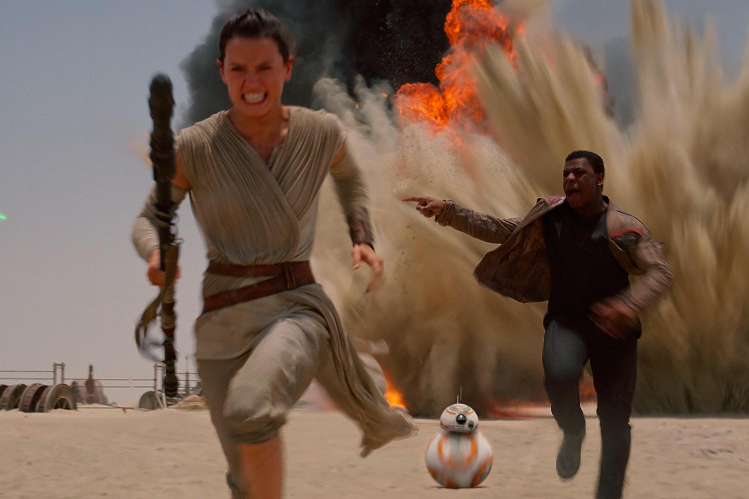 Rey runs from an explosion in Star Wars: The Force Awakens.