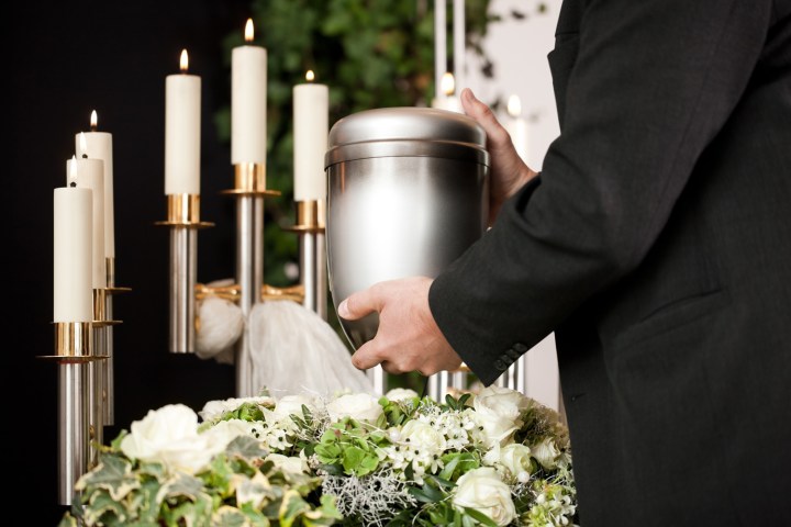 dna home storage man placing urn by candles at funeral