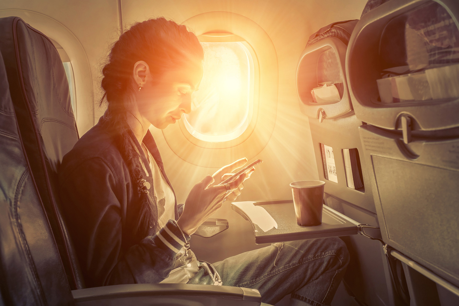 alaska airlines solar eclipse woman typing on phone in airplane sunlight