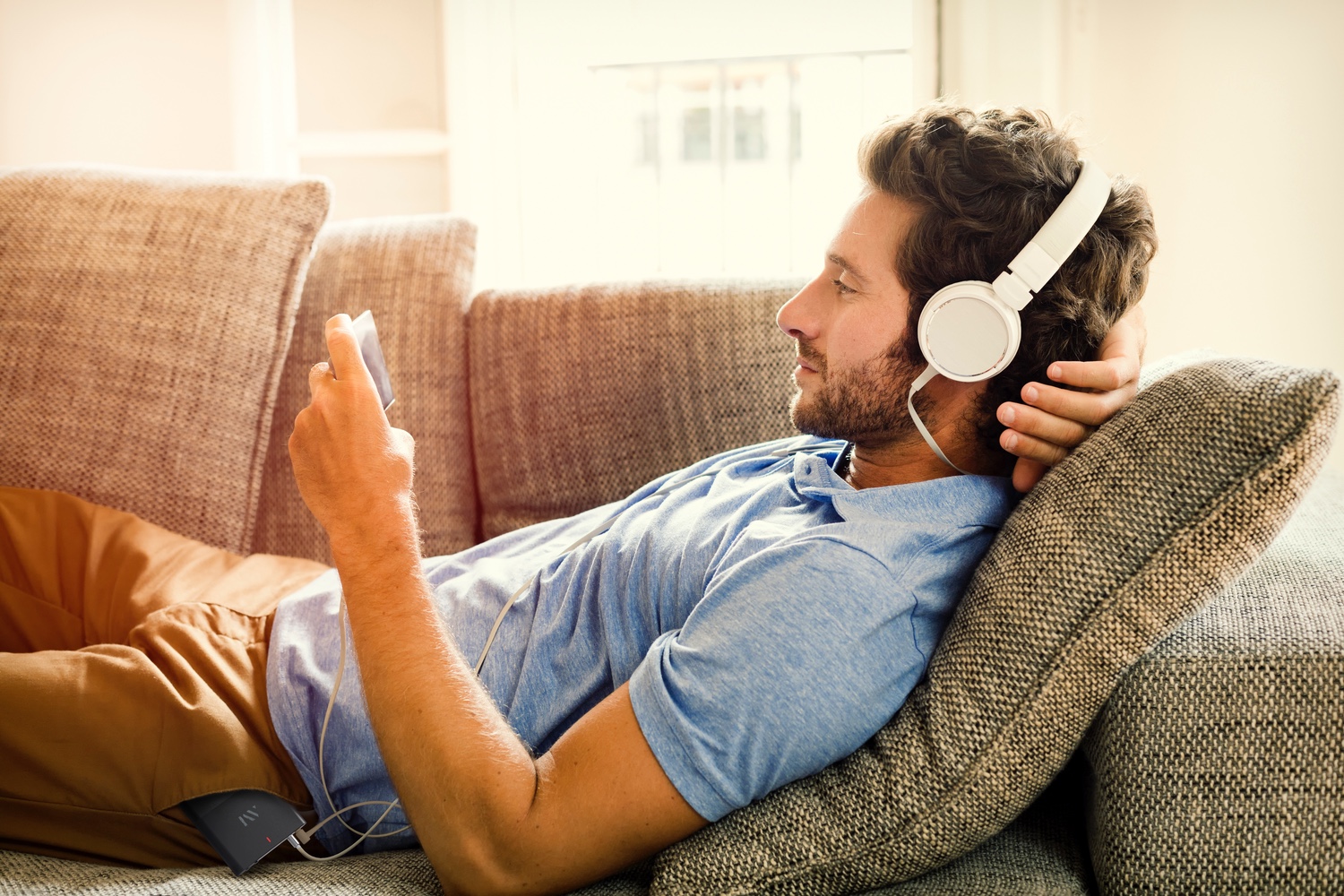 aftermaster pro fixes tv movie audio issues man on couch watches a mobile phone