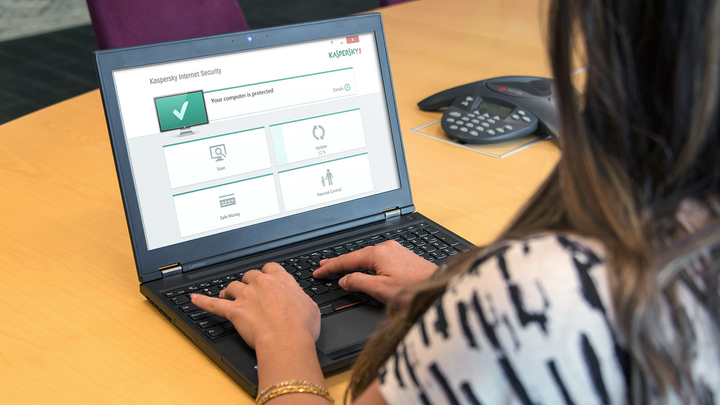A close up of a woman using a laptop displaying Kaspersky software on its screen.