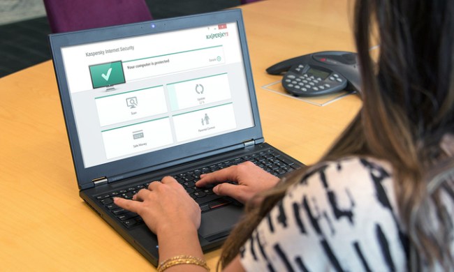 A close up of a woman using a laptop that is displaying Kaspersky software on its screen.