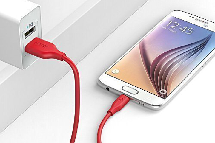 Anker PowerLine Cable in red plugged into a socket, with a phone charging at the other end.