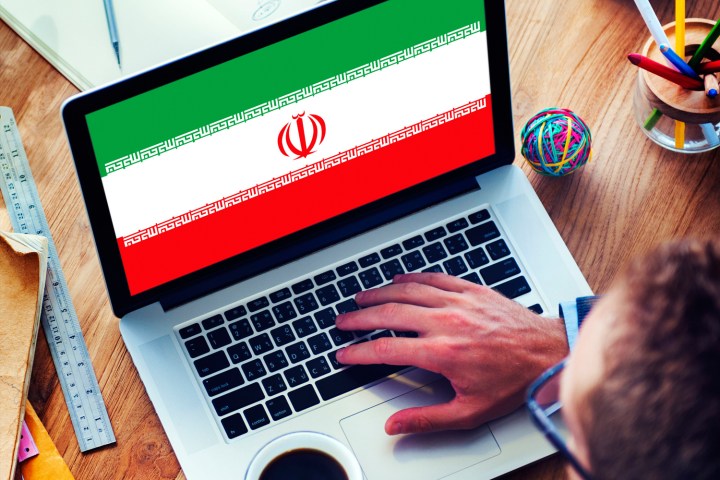 Hand on a computer with the Iranian flag on its screen