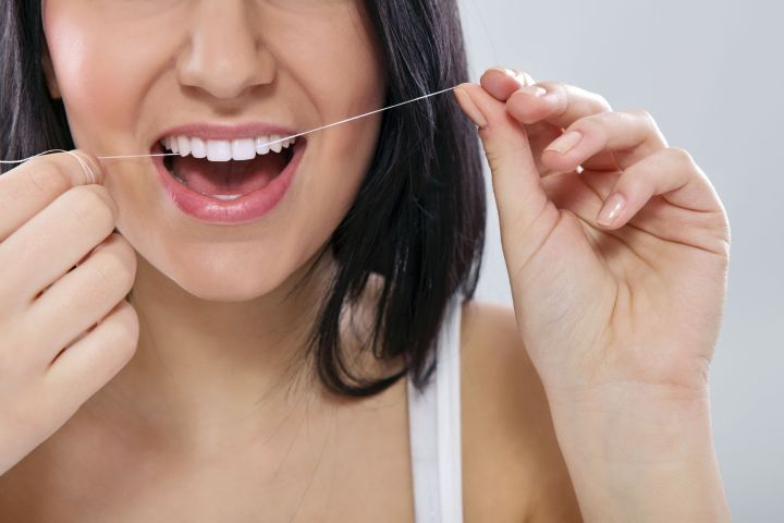 max flossolution 12781470  close up of a woman flossing his teeth with dental floss
