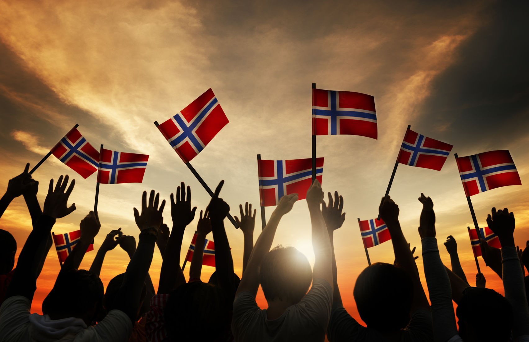 norway ev incentives extended 31310464  group of people waving norwegian flags in back lit