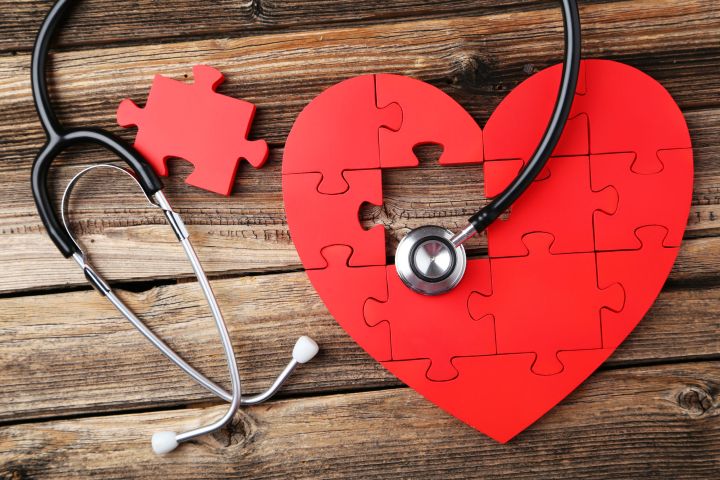 40576178 - red puzzle heart with stethoscope on brown wooden background