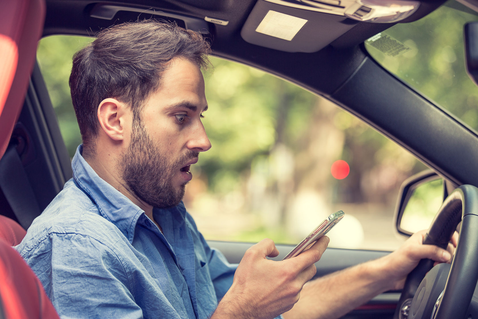 france texting while driving man sitting in car with mobile phone hand