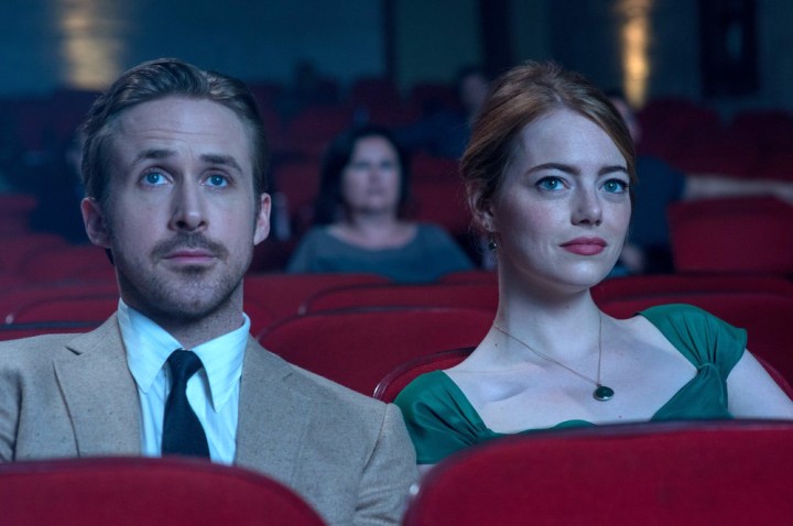 Ryan Gosling and Emma Stone sit next to each other in a theater.