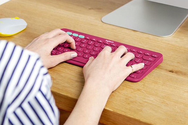 A person typing on a Logitech K380 Bluetooth keyboard.