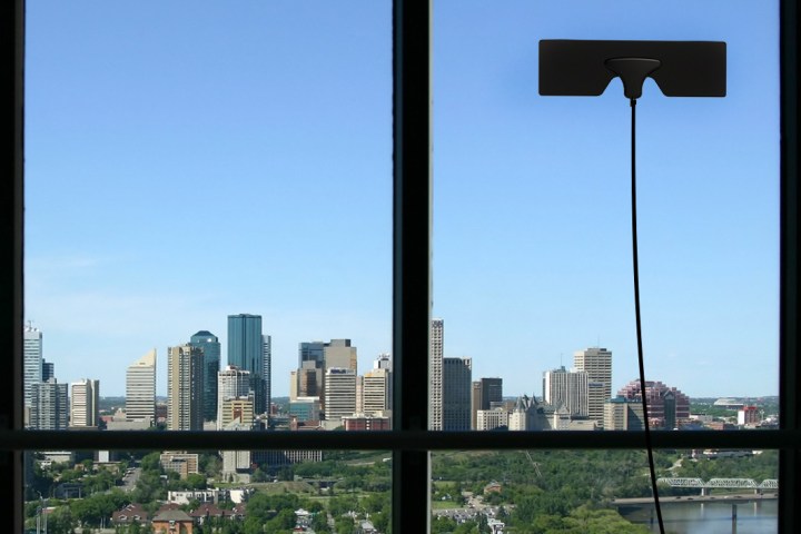 The Mohu Leaf Metro TV antenna secured to a window overlooking a cityscape.