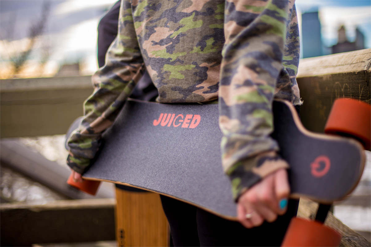 juiced electric skateboard girl holding juicedboard behind back