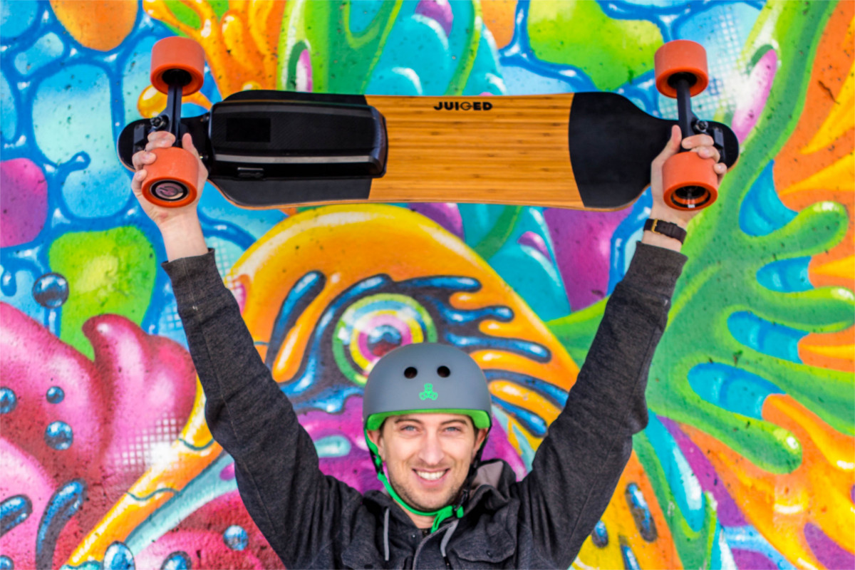 juiced electric skateboard man holding board above head