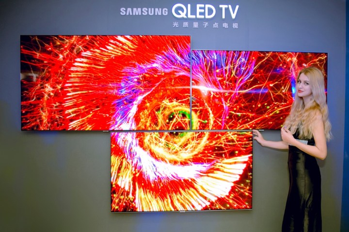 Samsung QLEDs on display with a model standing next to them.