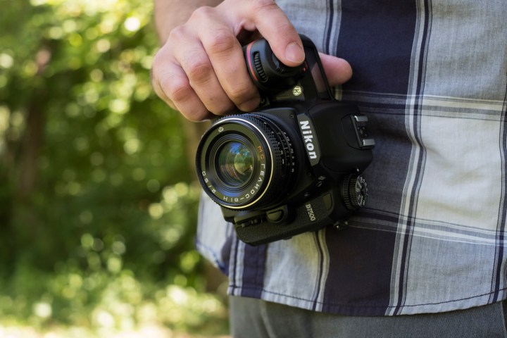 The D7500 held with one hand facing the front of the camera