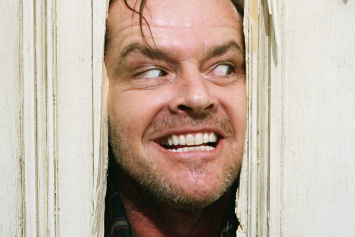 Jack Torrance olhando por um buraco em uma porta em "O Iluminado".