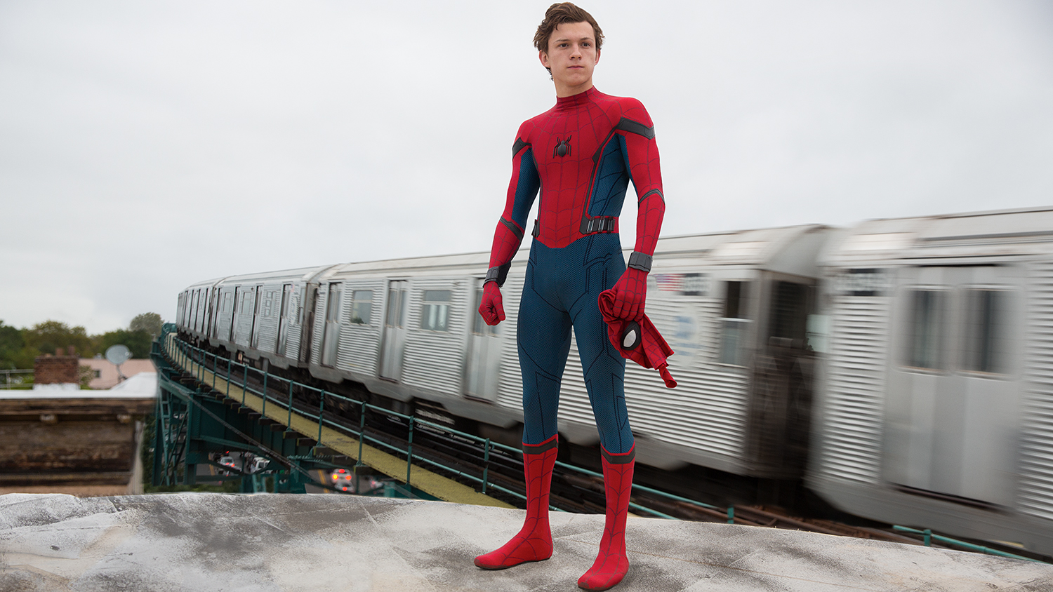 Spider-Man with his mask off standing atop a train in Spider-Man: Homecoming.