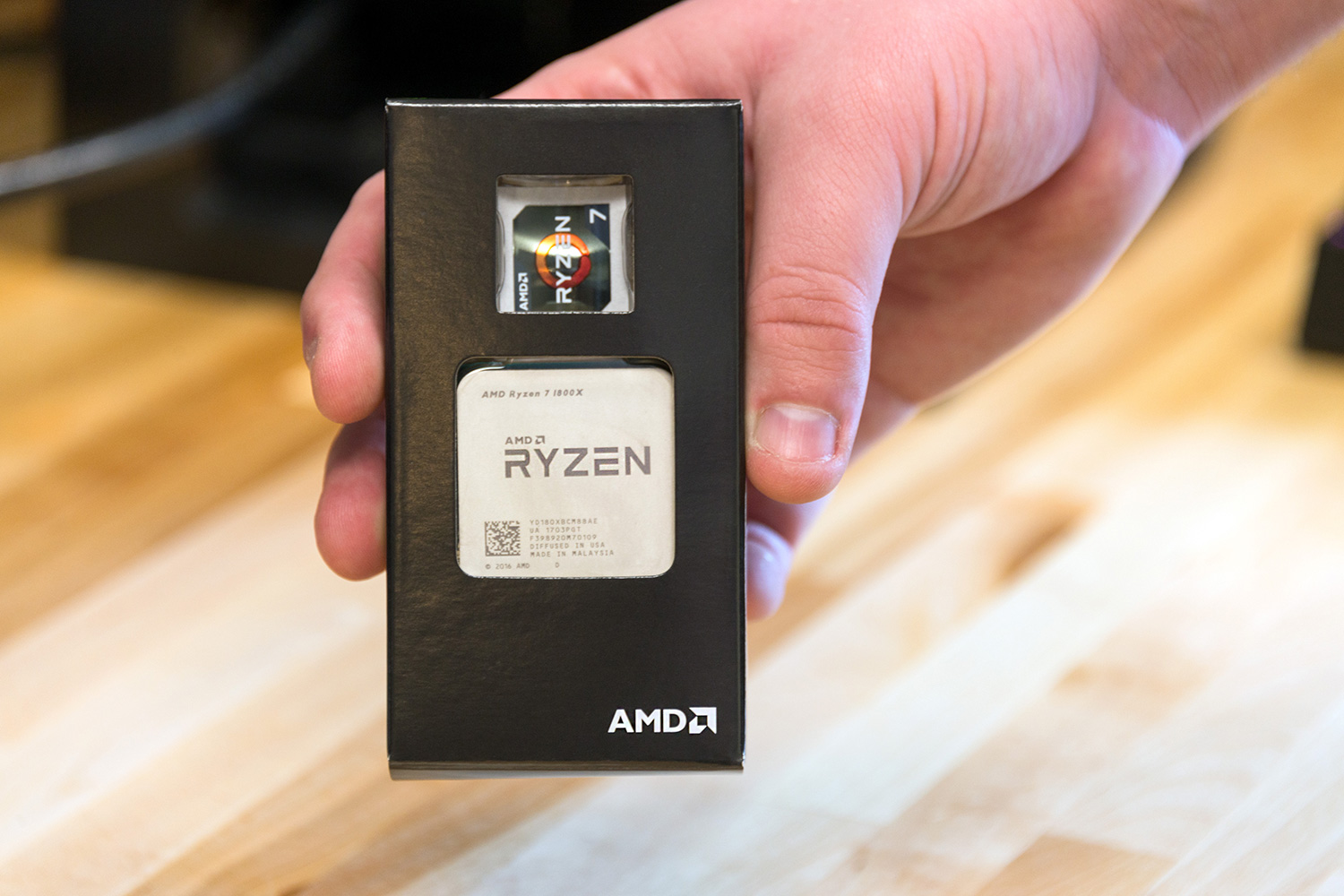 Caixa AMD Rizen CPU 7 sendo segurada em uma mão.