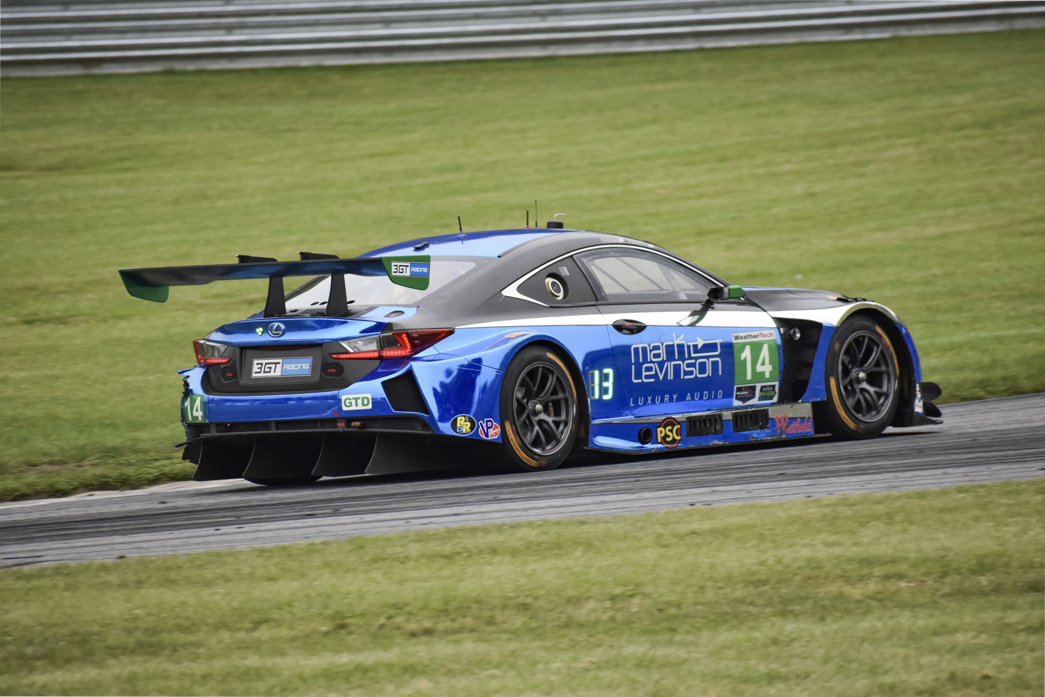 Lexus RC F GT3 driving off on a race track showing off the backside of the car and spoiler