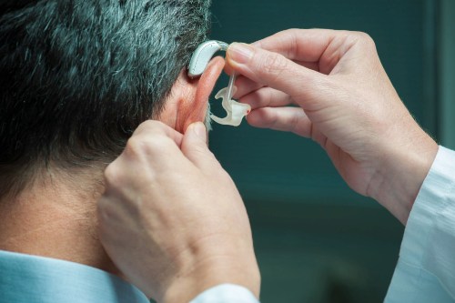 Audiologist fitting a patient's hearing aid.