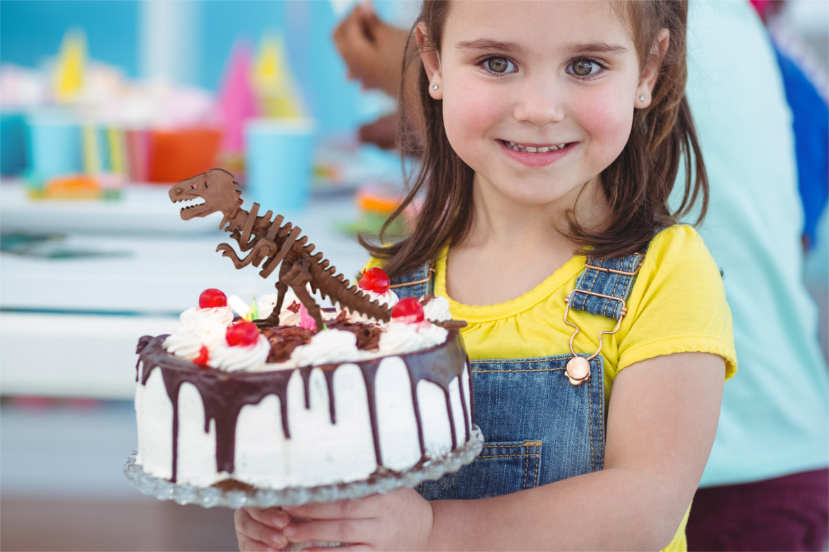 chocolate construction t rex smiling girl holding birthday cake at the party