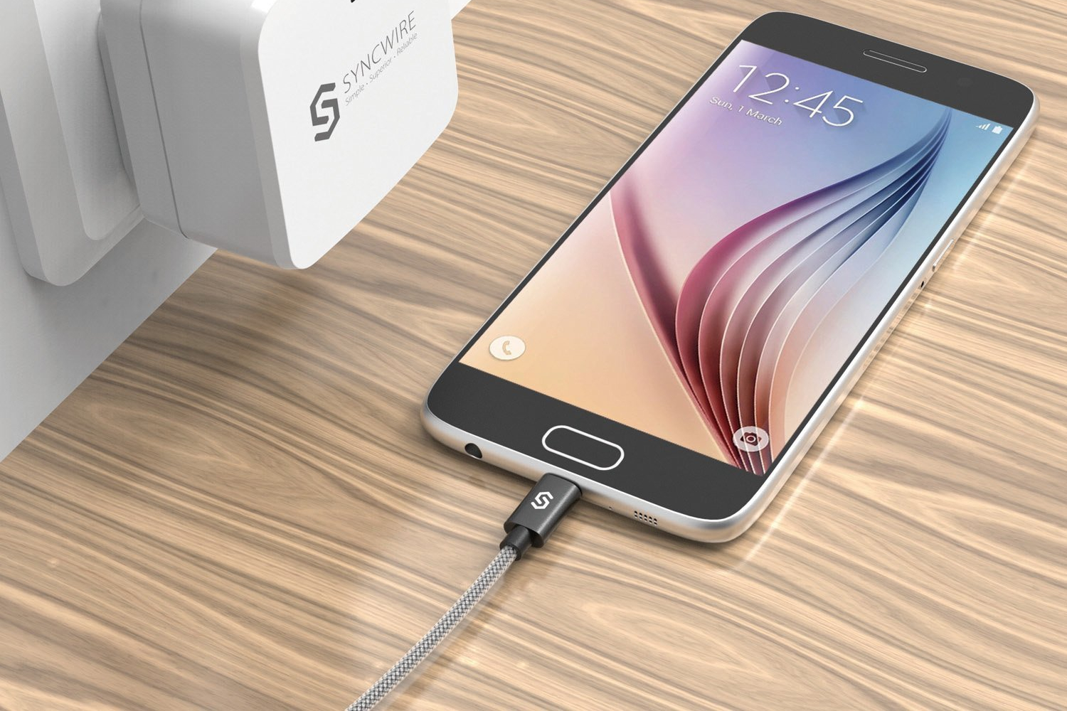 Syncwire Micro USB cable plugged into a smartphone next to a charging plug.