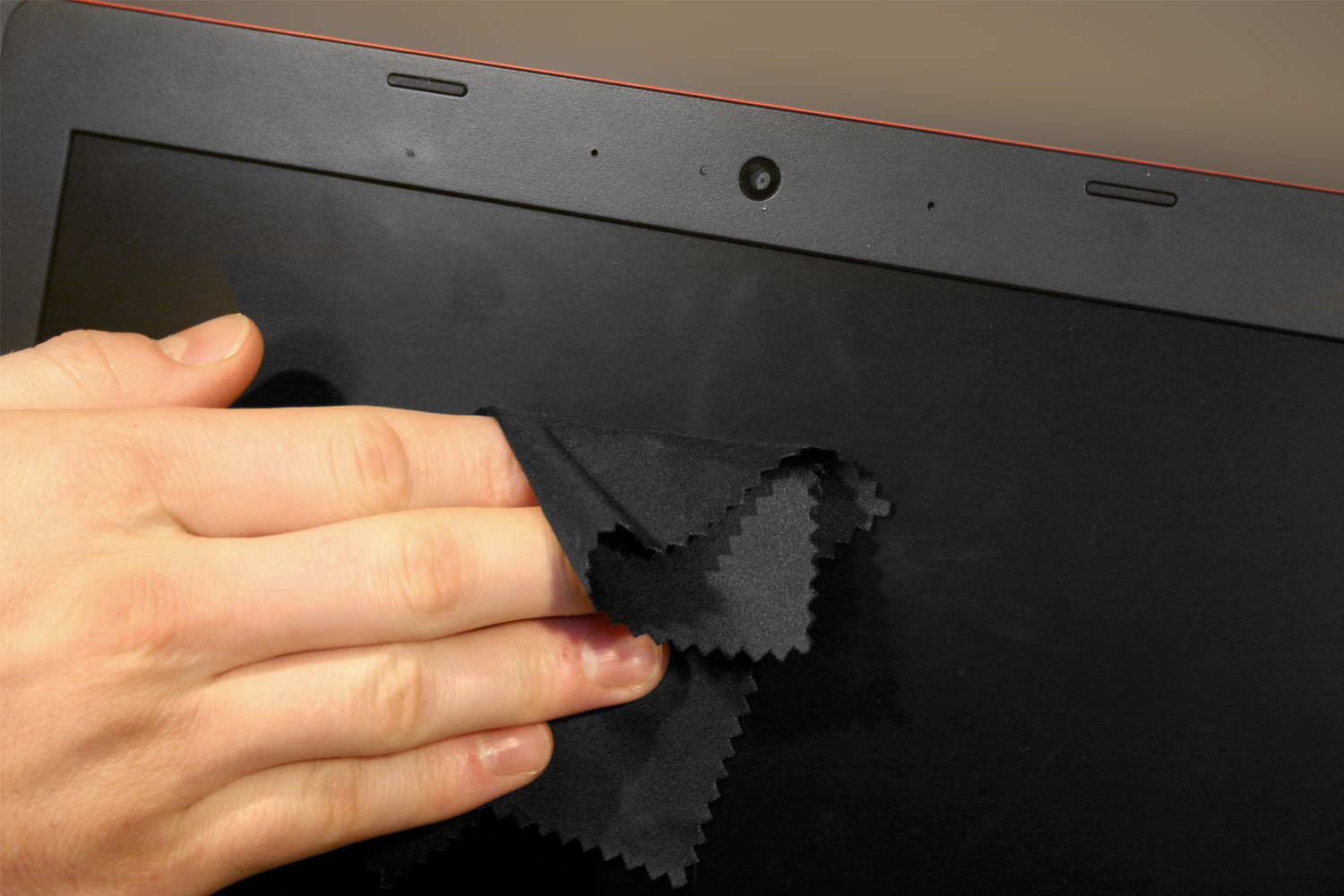 Person's hand cleaning a laptop screen with a microfiber cloth.