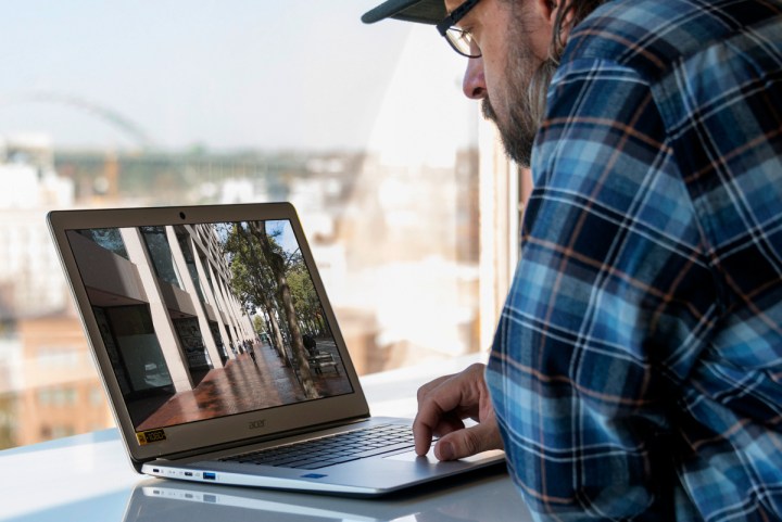 A person sitting at an Asus Chromebook 15 and using it.