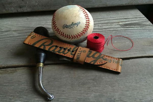 The Strap Smith Baseball Glove Strap next to a baseball and red thread.