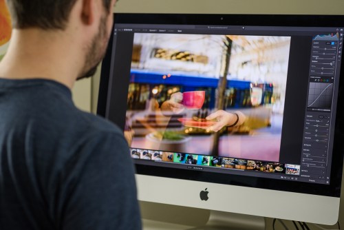 A person using Adobe Lightroom CC on an iMac.