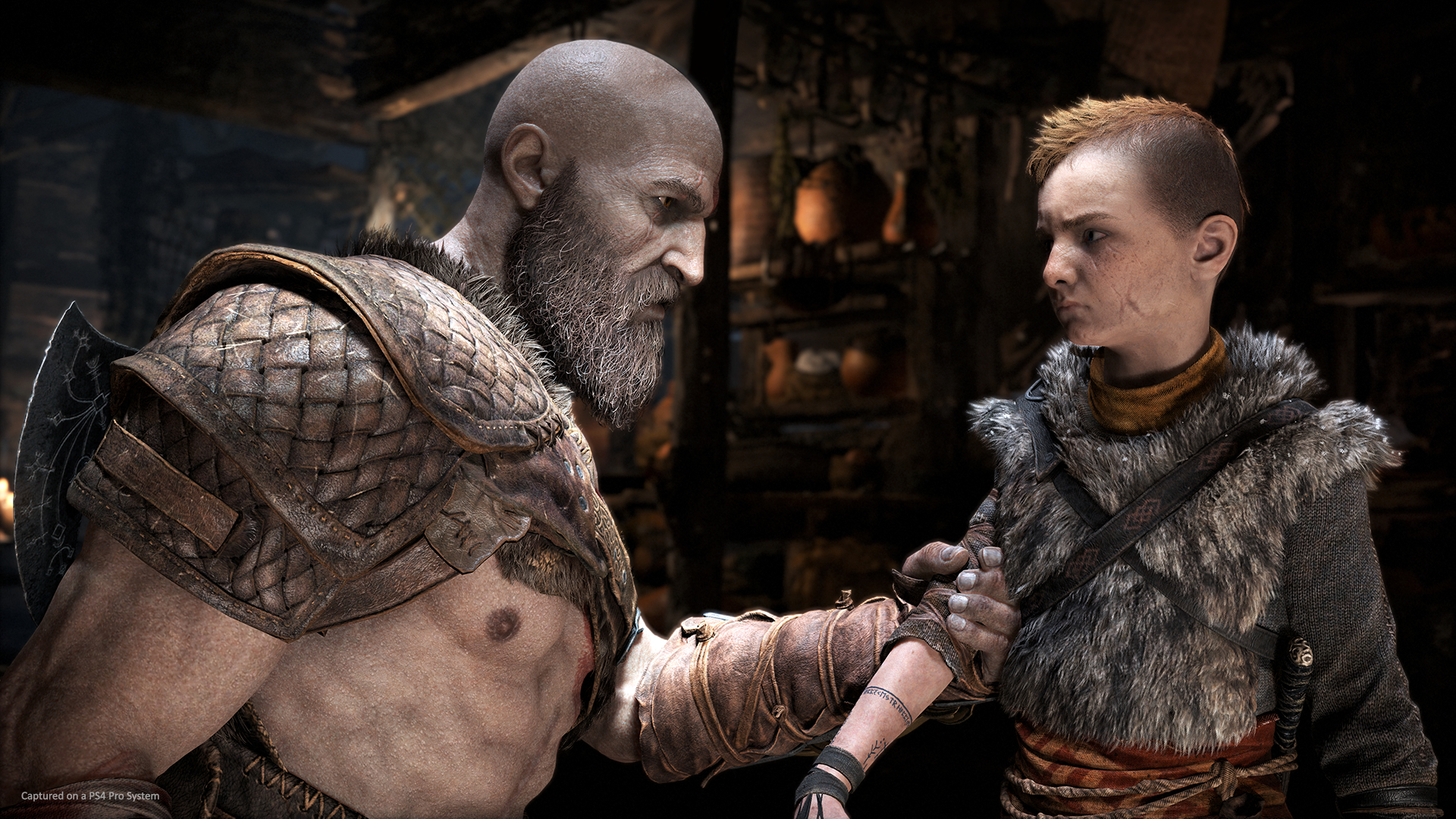 Revisão de Deus da Guerra |  Kratos agarrando o braço de Atreus enquanto falava com ele em uma casa