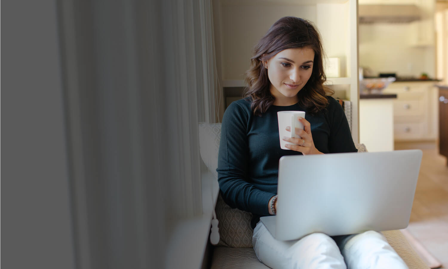 Mulher relaxando em casa com laptop e café.