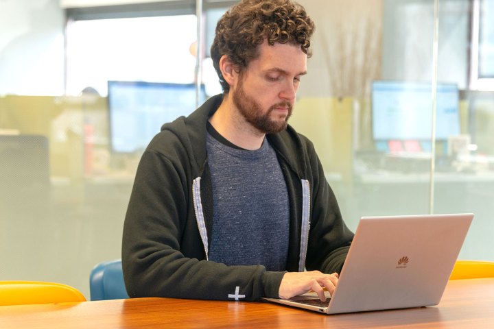 A person typing on a Huawei MateBook X Pro laptop at a table.
