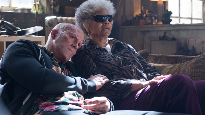 Ryan Reynolds y Leslie Uggams como Deadpool y Blind Al sentados en un sofá con Deadpool apoyando su cabeza en el hombro de Al en Deadpool 2.