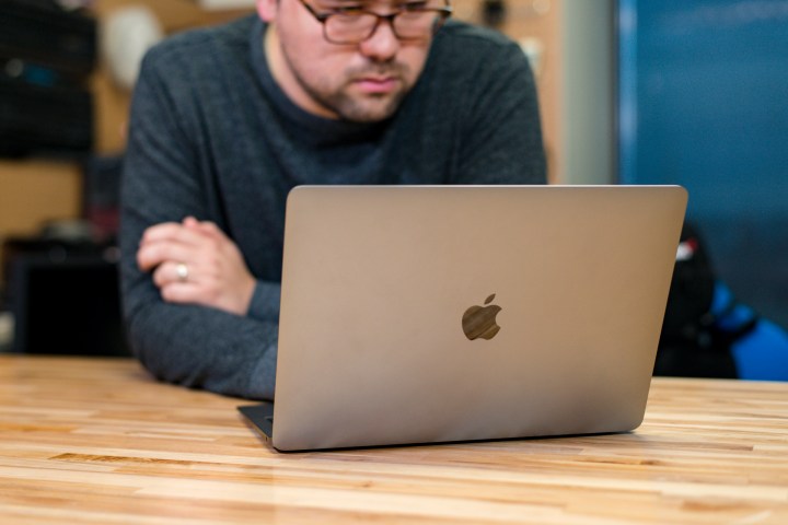 A person working at a 2018 Macbook Air at a wooden table.