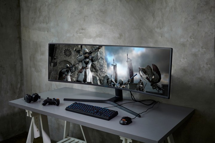 The 49-inch Samsung CRG9 Dual QHD Cueved QLED Gaming Monitor in use, with Assassin's Creed on the screen.