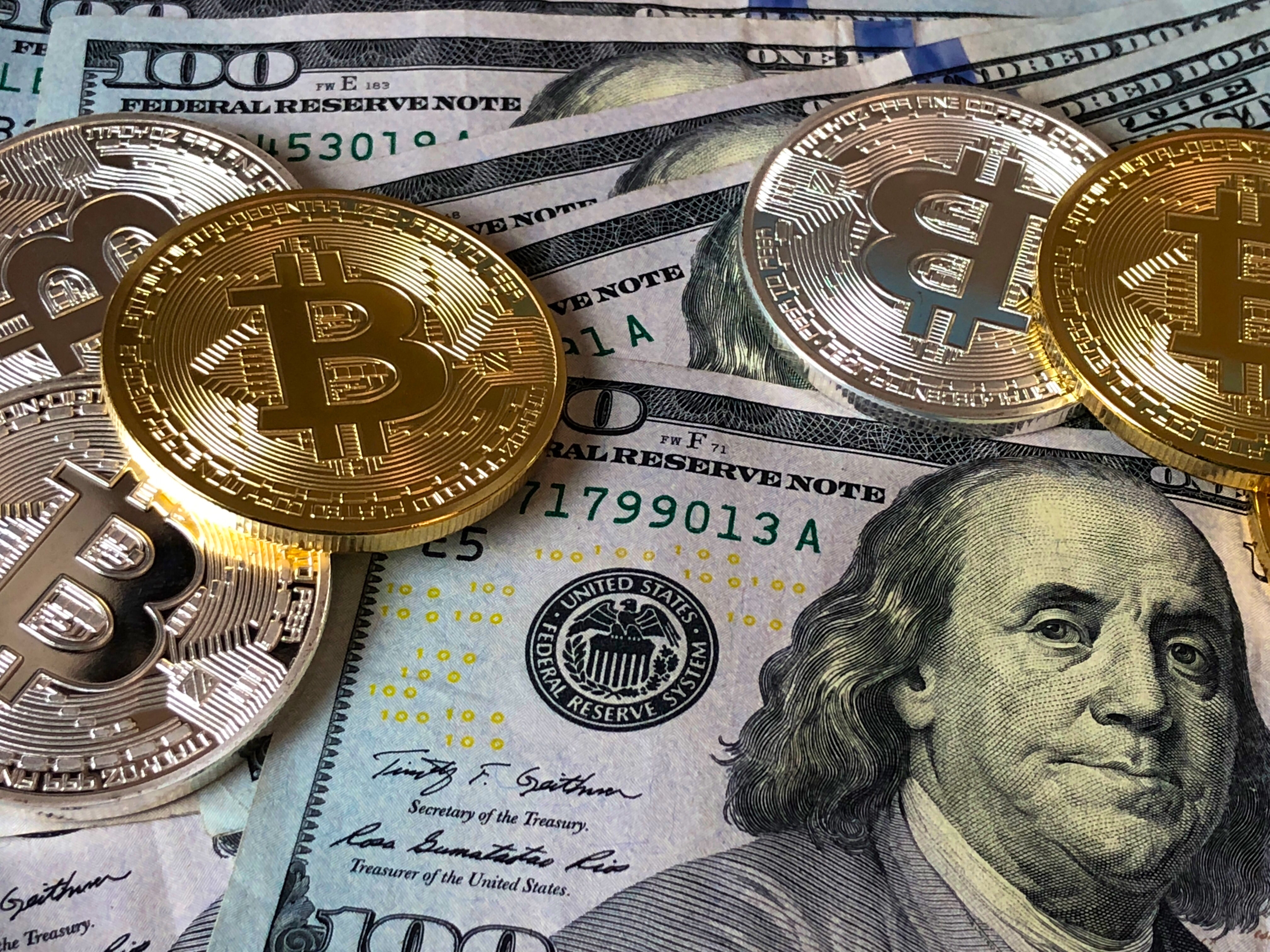 stock photo of bitcoins and U.S. dollar bills