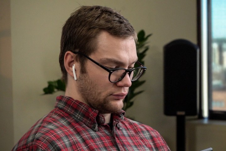 A man wearing Apple AirPods while sitting indoors.